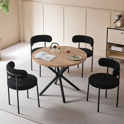 Gepolsterte Esszimmerstühle in Schwarz als 4er-Sitzgruppe an einem runden Holztisch